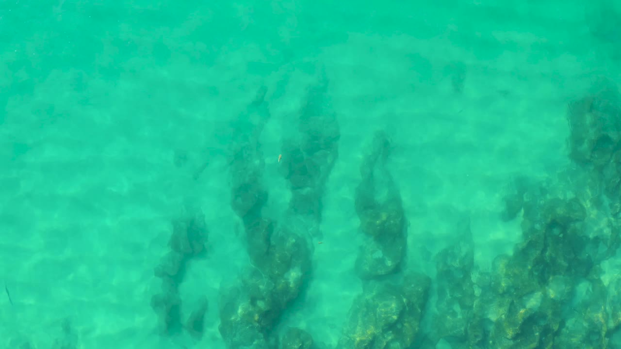 Rippled turquoise water reveals clustered rocky formations below the surface at Laguna Beach Los Cabos, with no visible people.