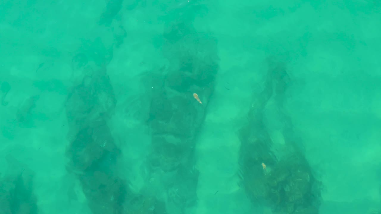 Sun glint above submerged rocks in turquoise water