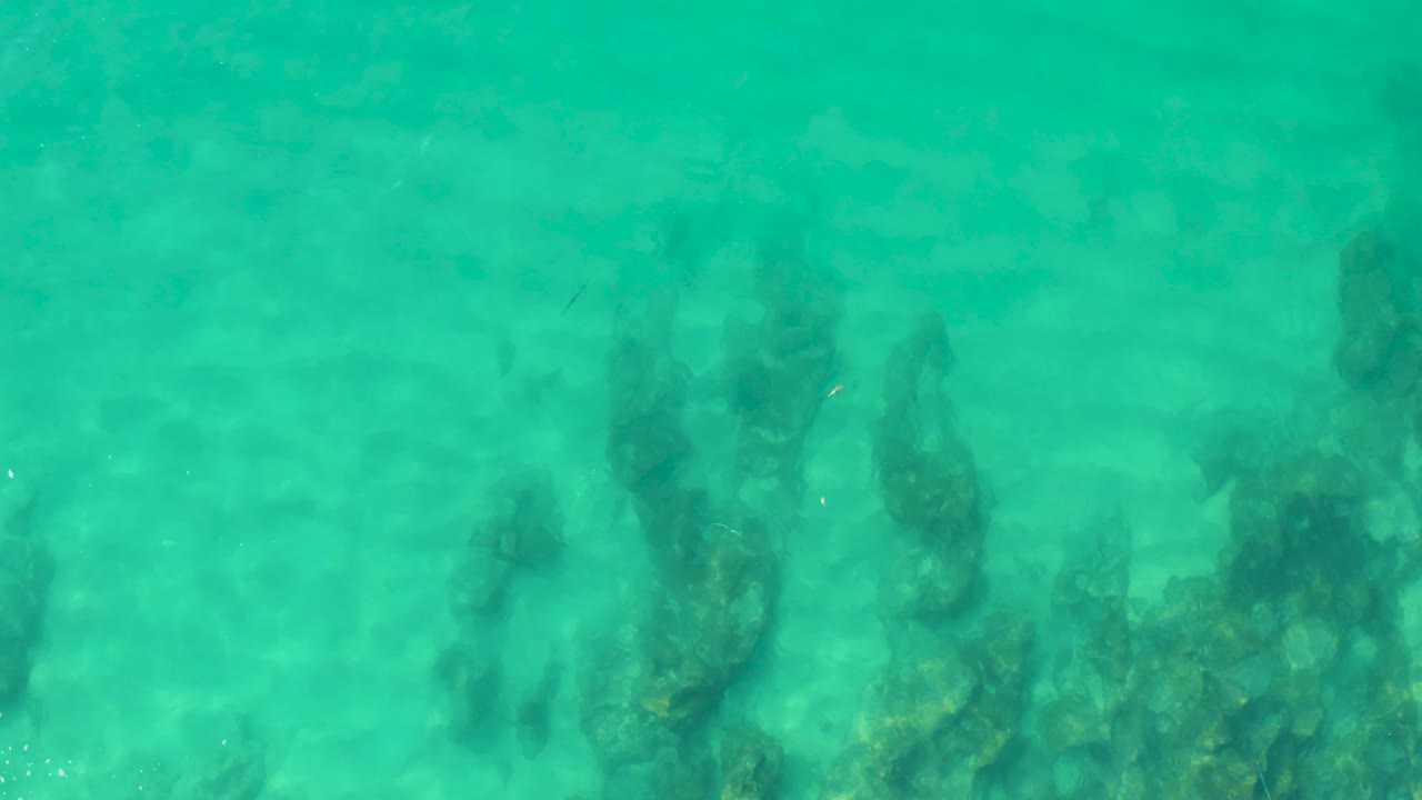 Turquoise ocean water at Laguna Beach Los Cabos shows dark coral-like underwater forms softened by surface ripples, with no visible people.
