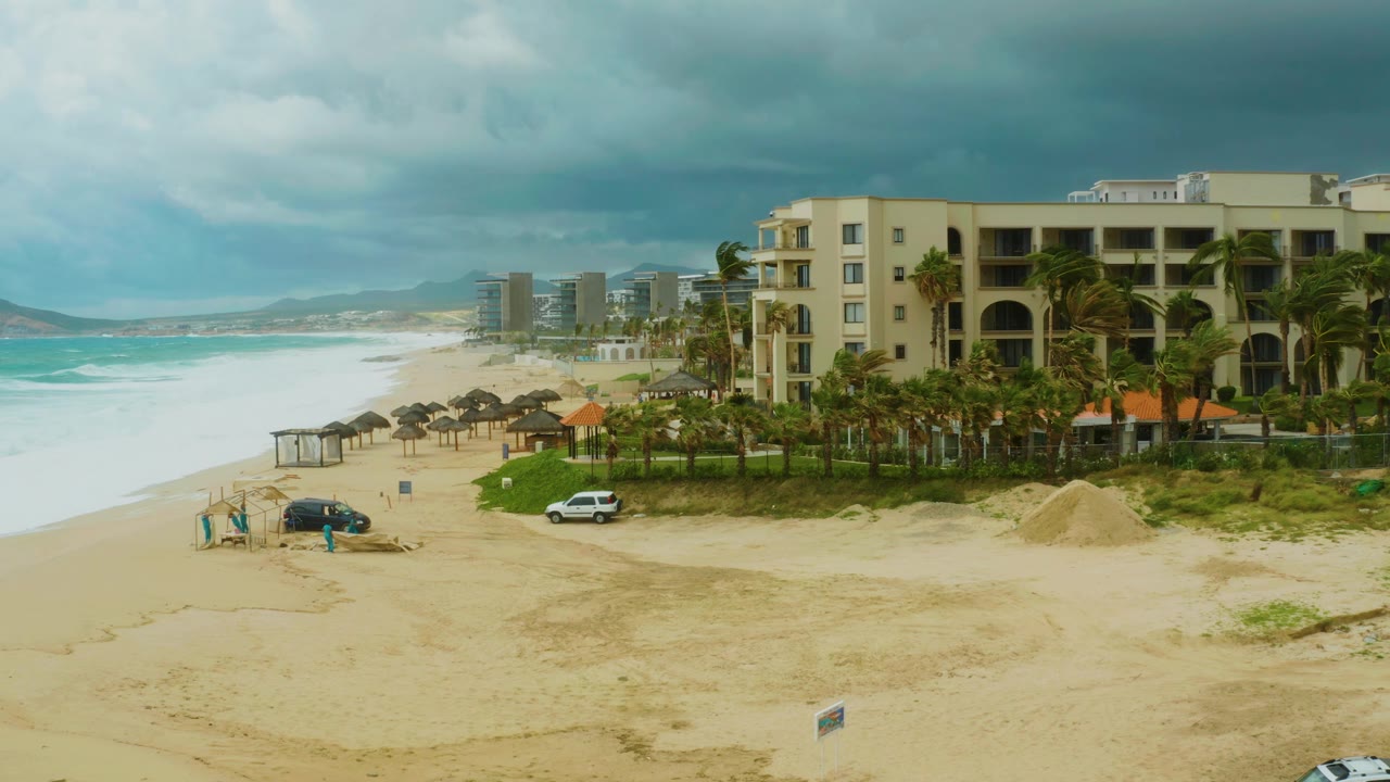 Beach vehicle near resort palms under cloudy sky