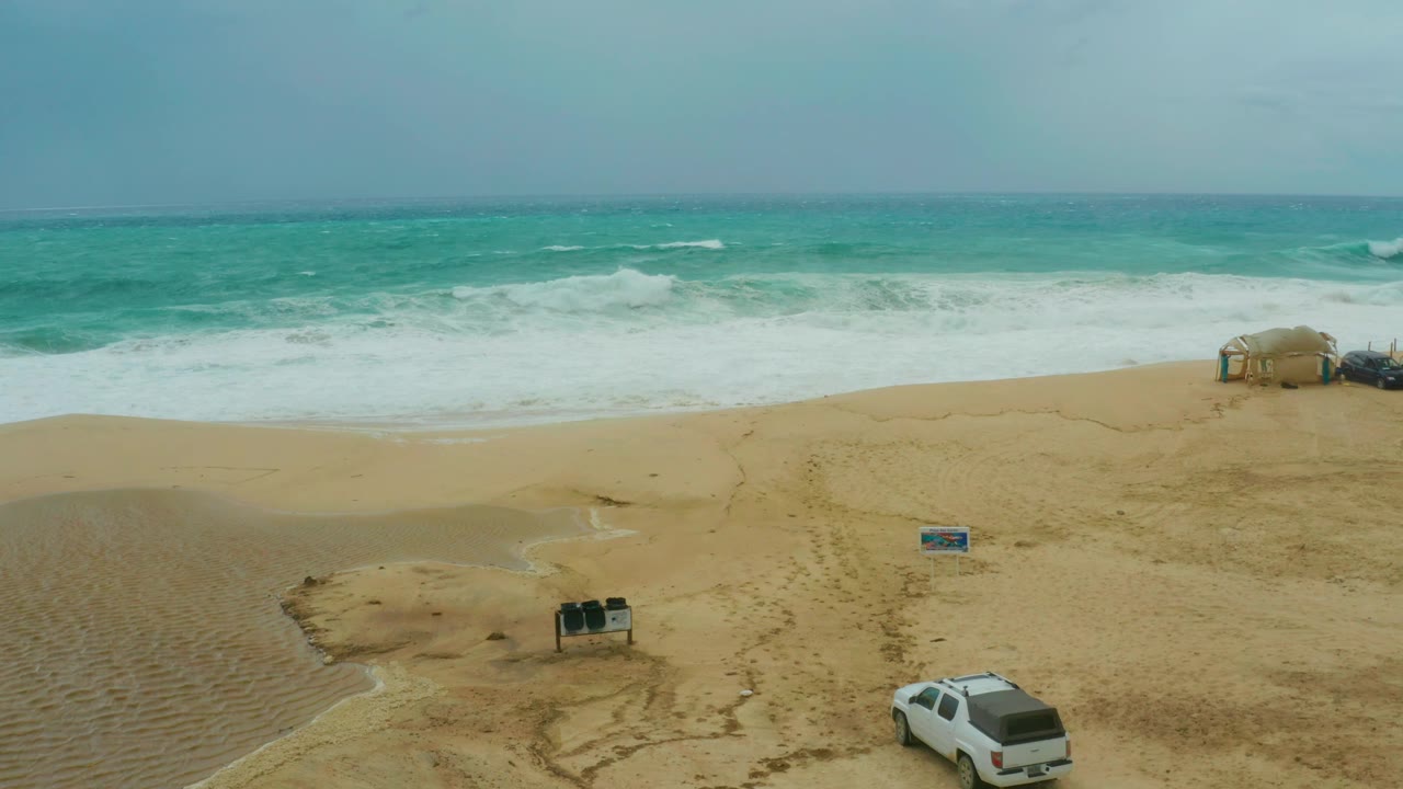 White SUV partly visible at bottom edge of beach frame.