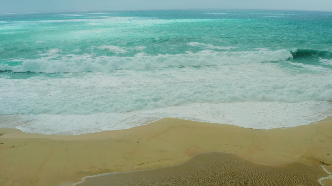 White waves washing farther up the sand