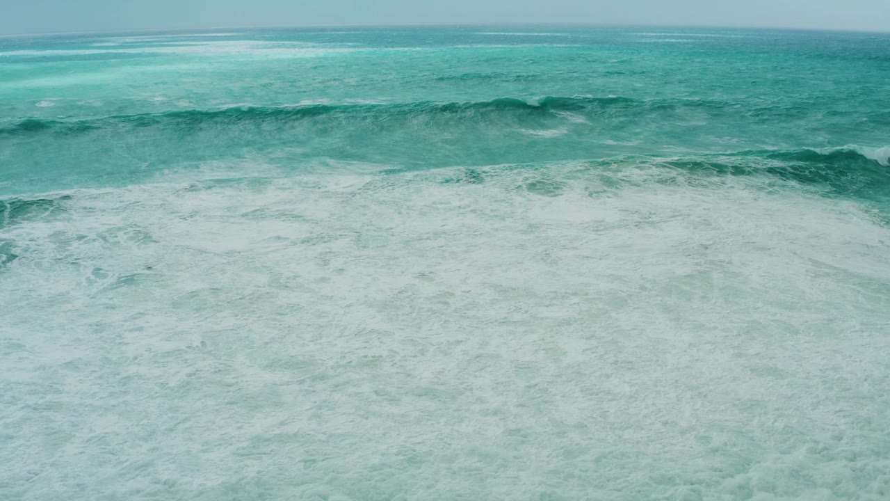 The wave face appears wider and more textured in the midground at Dreams Resort Los Cabos, with broken white foam spreading toward the lower edge, no visible people.
