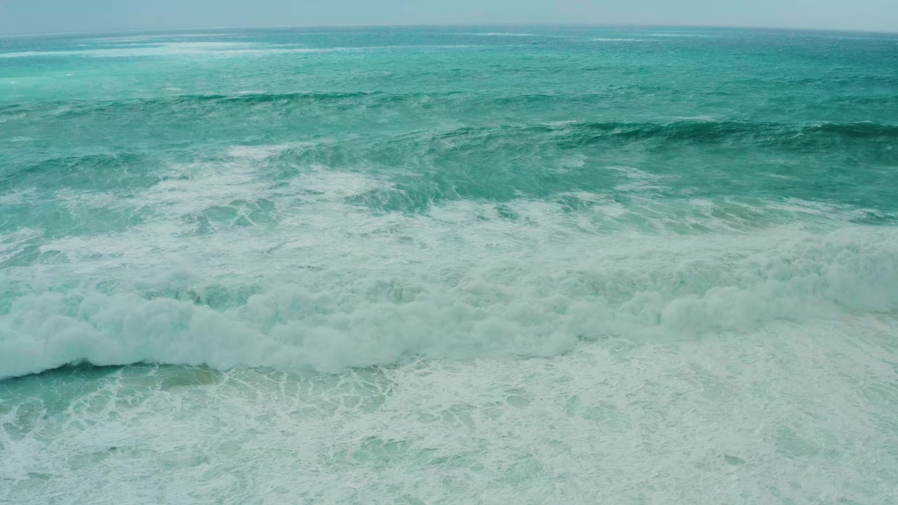 Turquoise ocean swell breaking into white foam