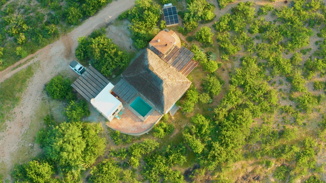 Closer overhead view of house, pool, car, and dirt road