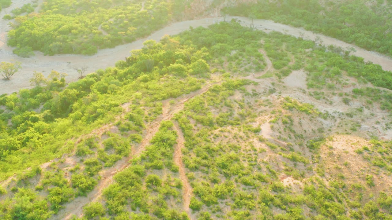 Green and sandy terrain with a winding channel across the top of the aerial frame.