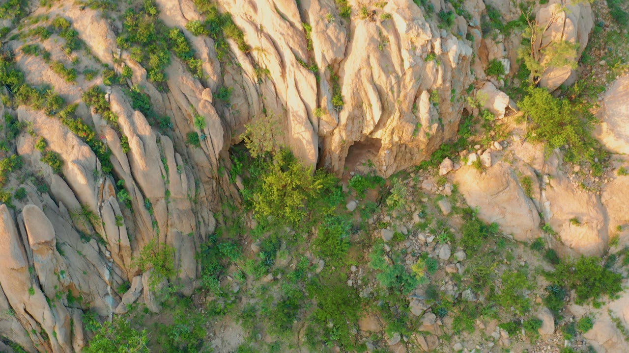 Overhead boulders and scrub vegetation on rocky slope