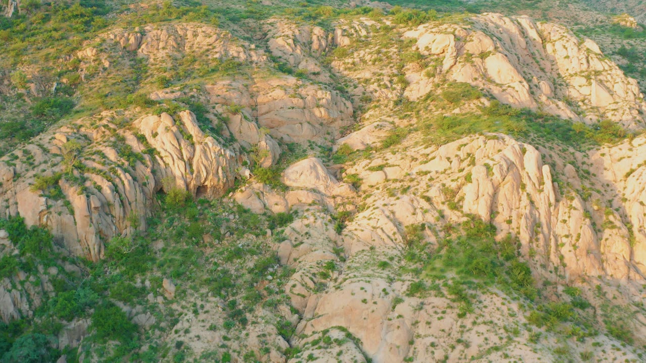 Tan rock formations with sparse green vegetation