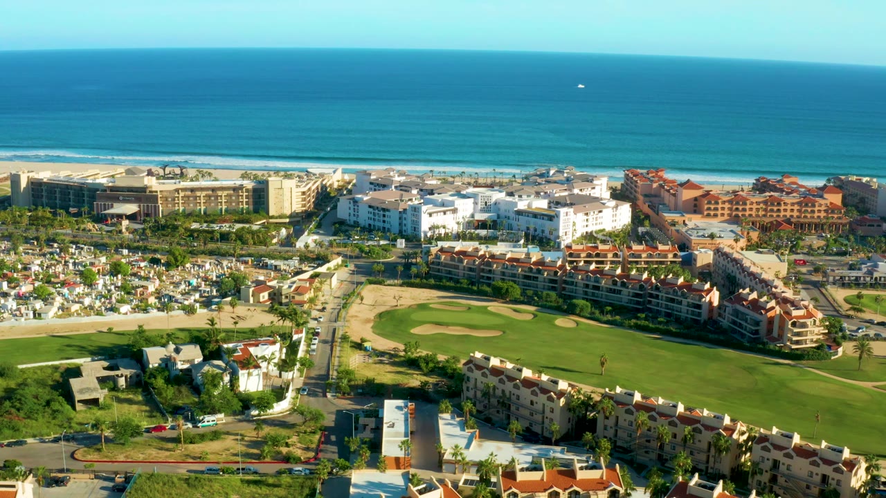 Aerial coastal development with fairway, road grid, beach, and ocean.