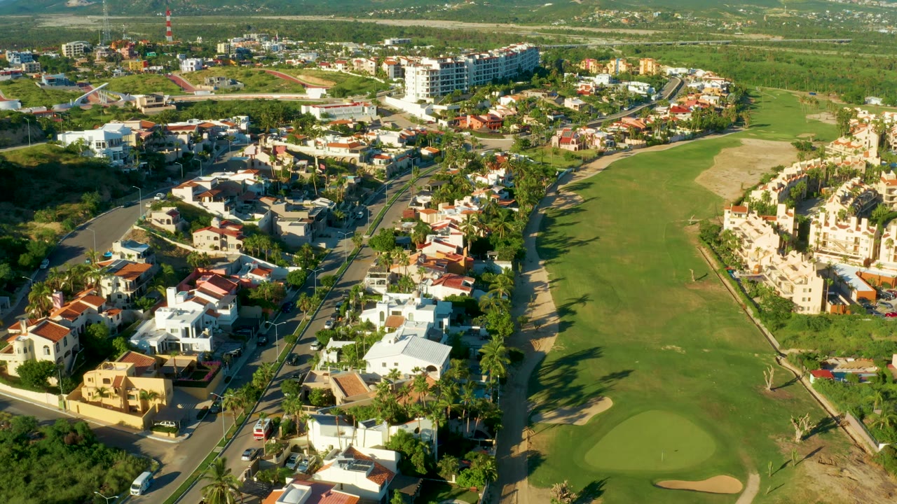 Aerial shot of a residential block, road, and golf green.