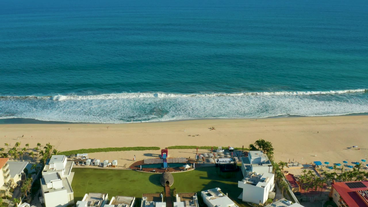 Ocean surf approaching a sandy beach beside resort grounds