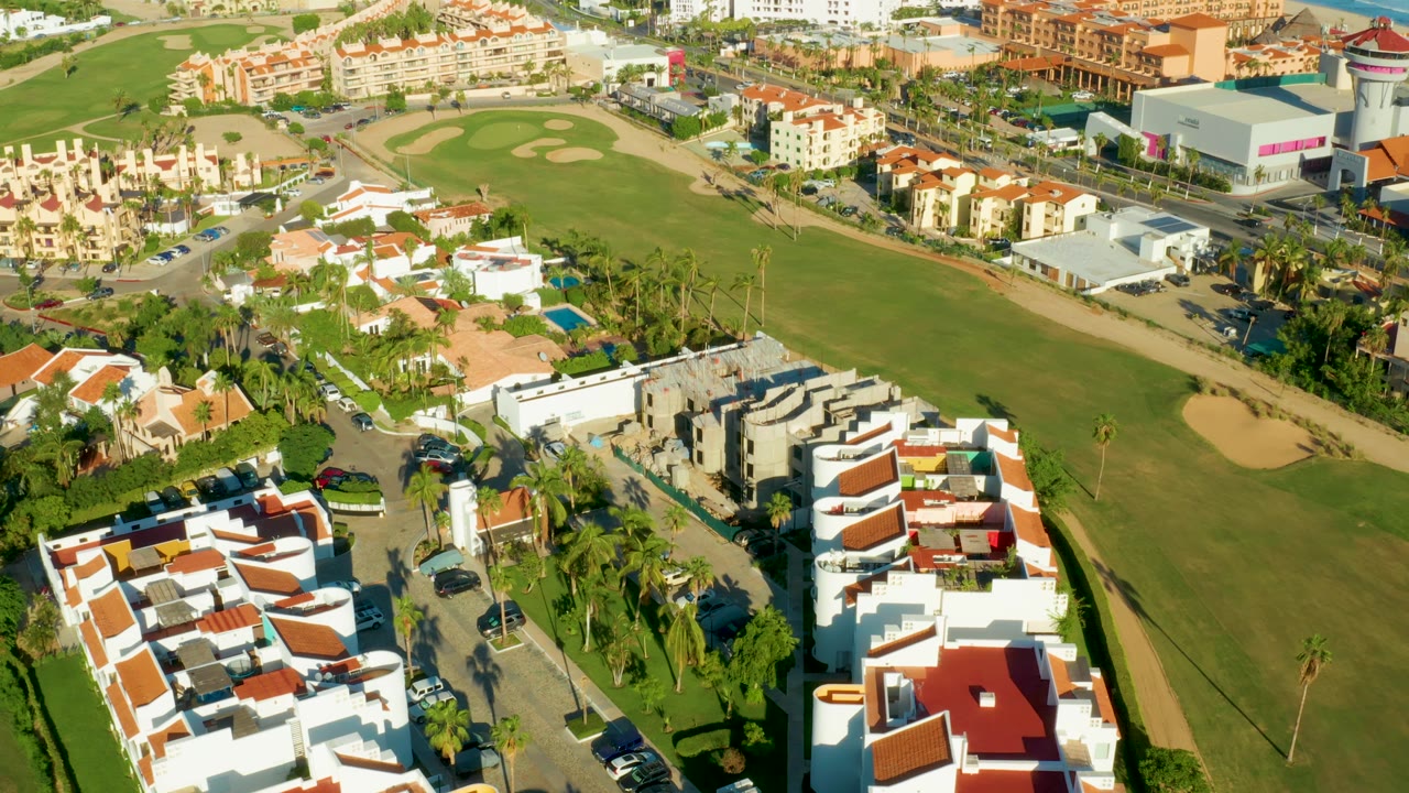Aerial neighborhood view with fairway and shopping-size buildings beyond