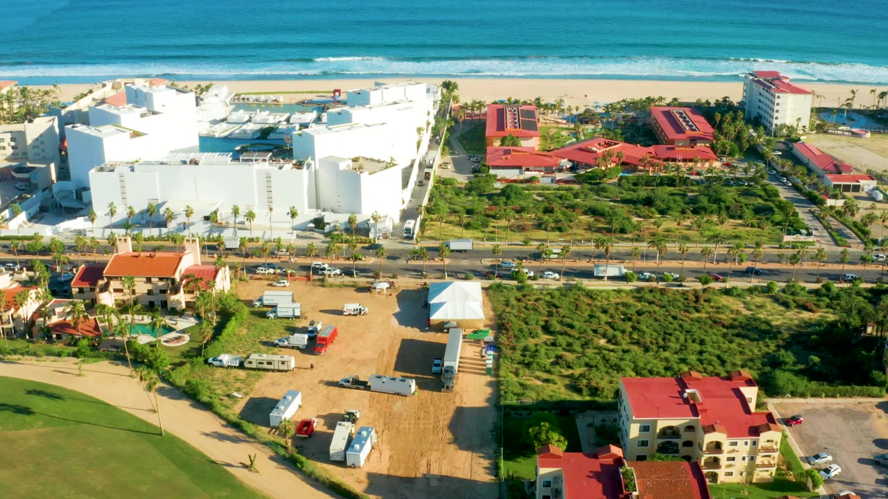 Coastal road traffic beside beach buildings and dirt construction areas.