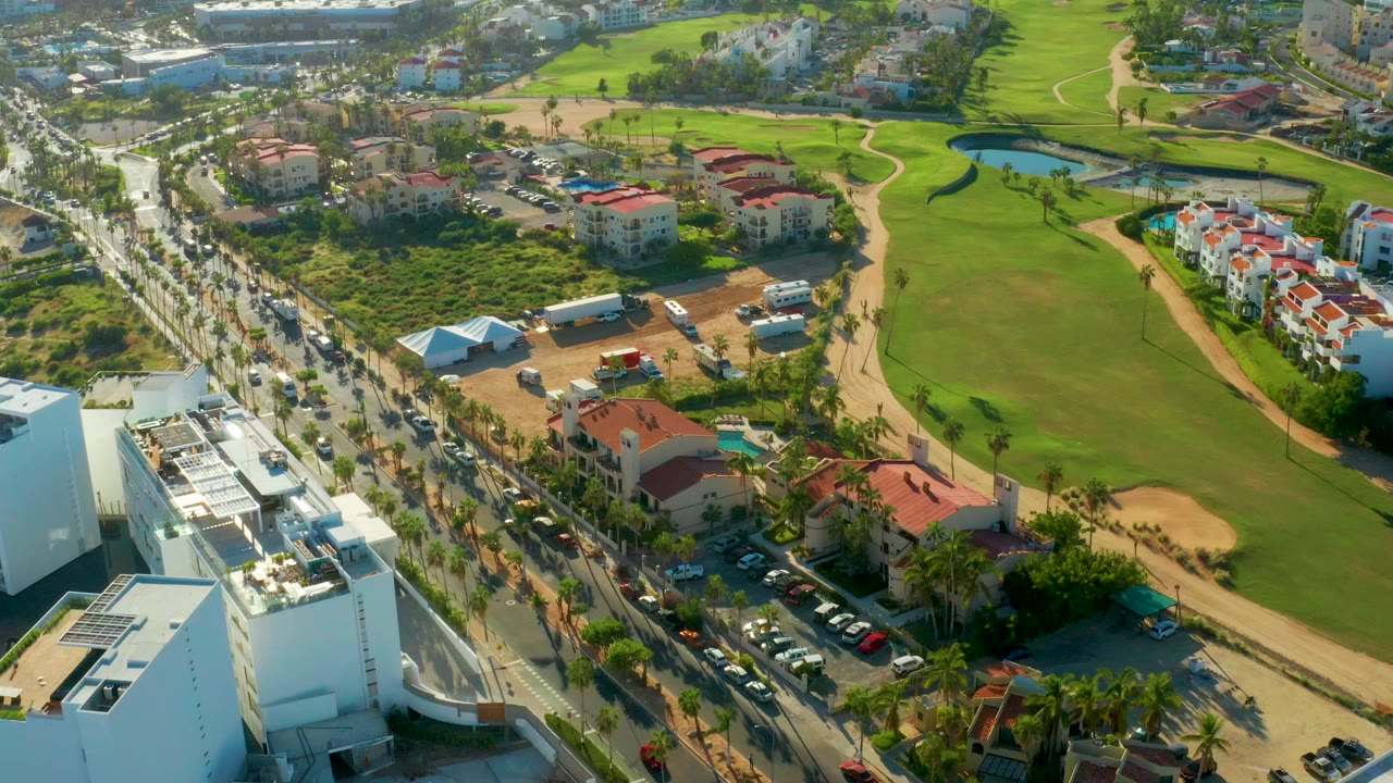 Aerial road traffic beside a green golf course and residential buildings.