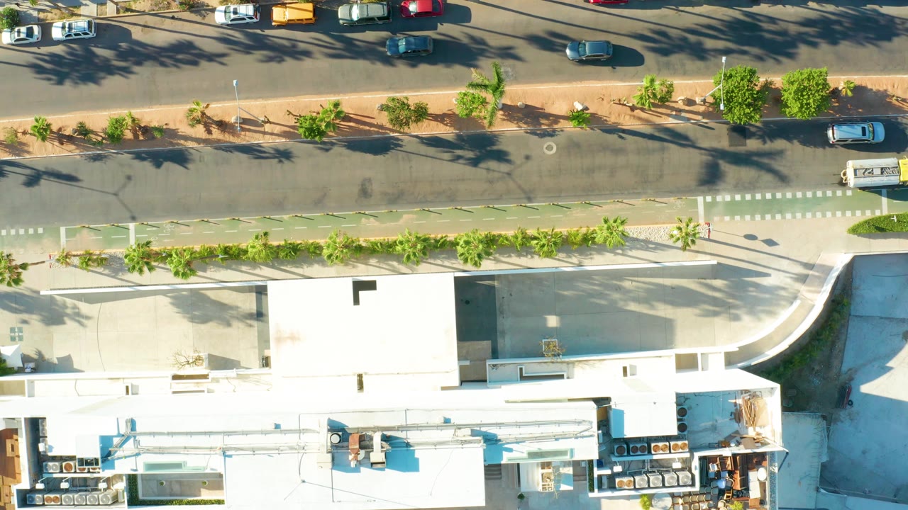 Overhead road with rooftops, trees, and parking