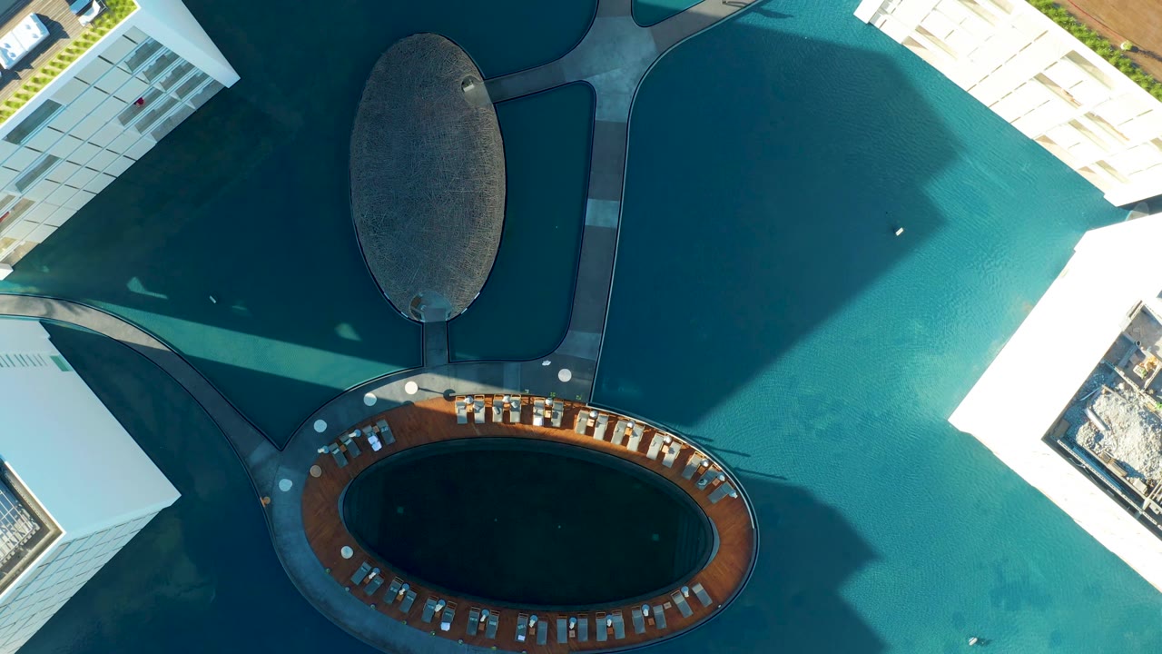 Overhead view of the oval plaza feature, surrounding water, and adjacent white buildings.