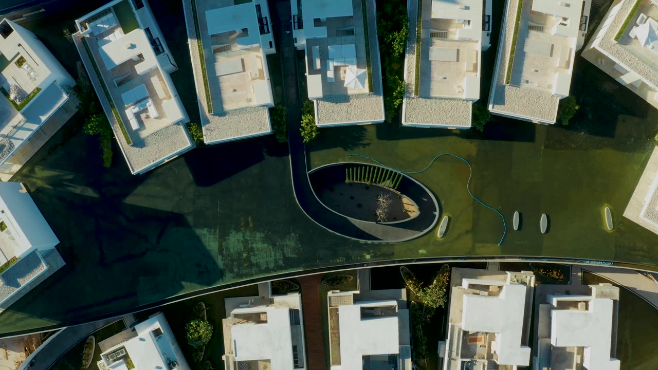 Overhead view of residential buildings beside a curved path and oval landscape feature.
