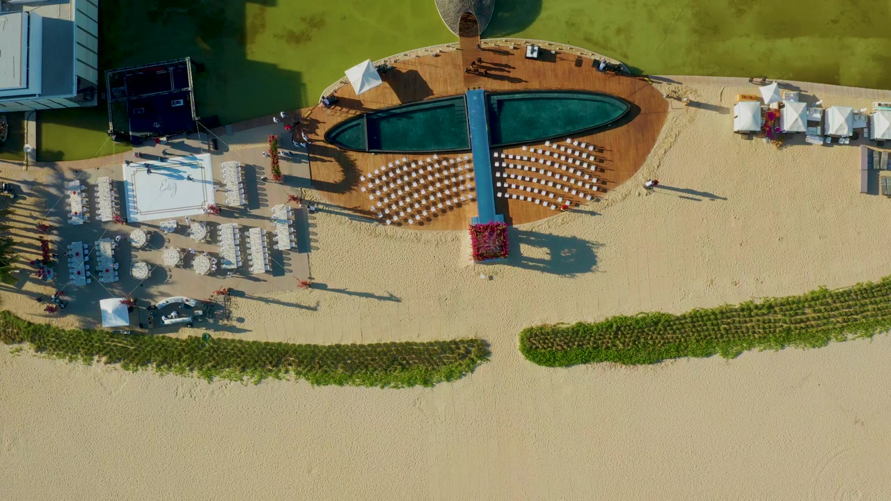 Aerial view of beach lounge rows beside a pool deck.