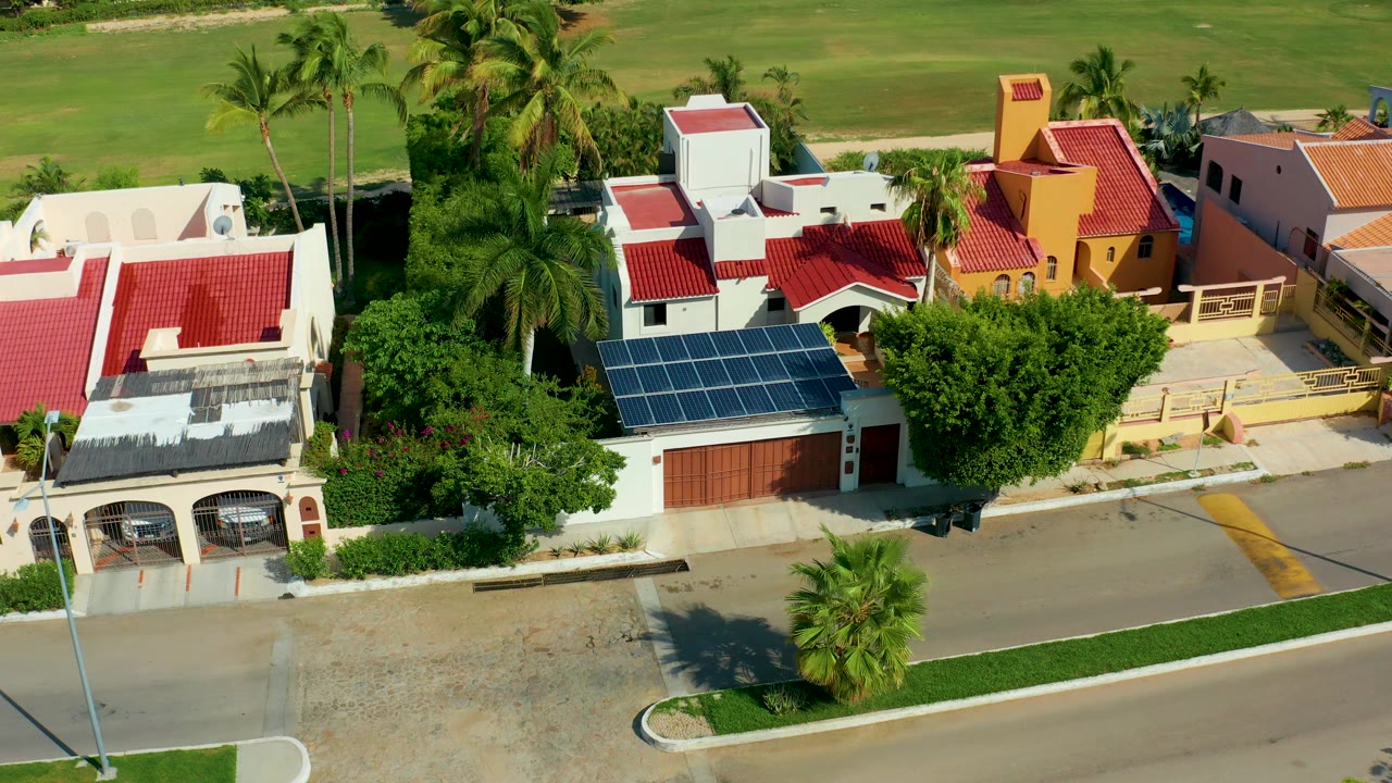Drone-style view of palm trees around homes with solar panels and red roofs.