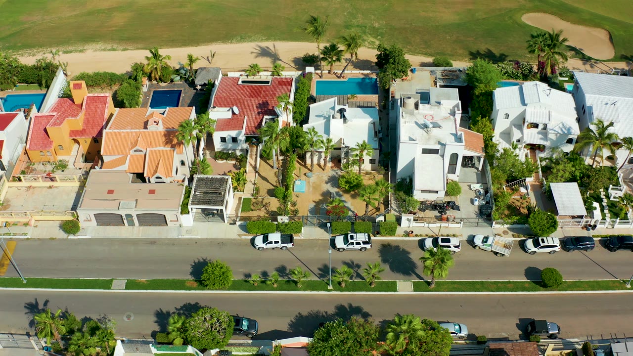 Overhead neighborhood frame with renovated roofs and cars on a quiet street.
