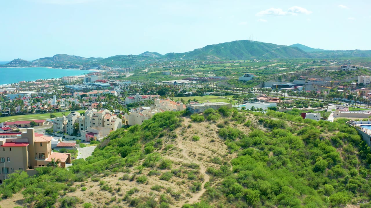 Sunlit hillside foreground with coastal buildings and mountains