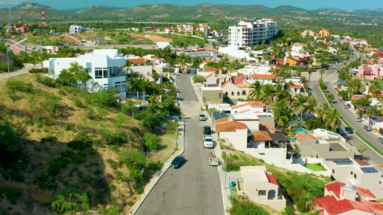 Residential hillside road with cars, palms, and modern homes