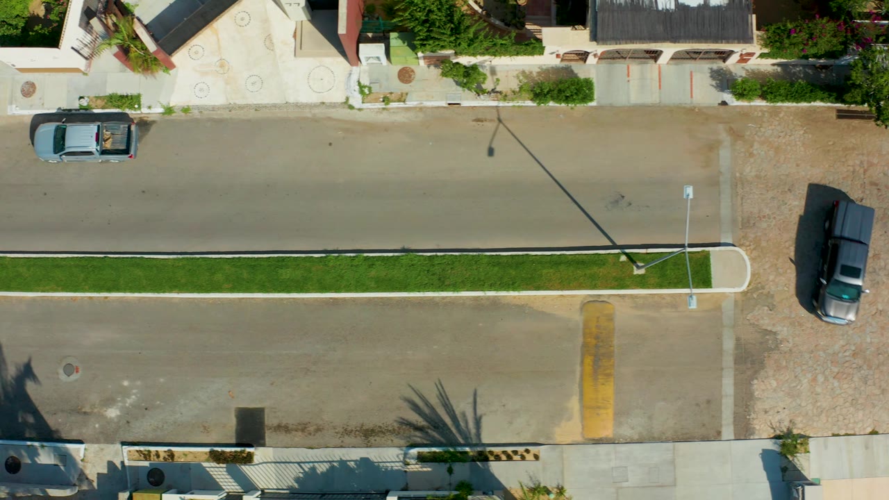 Residential overhead with light blue pickup on the road and dark vehicle near the lower-right driveway.