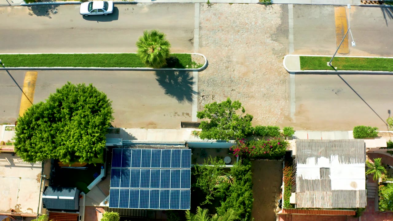 Residential block from above with solar panels, trees, road, and car
