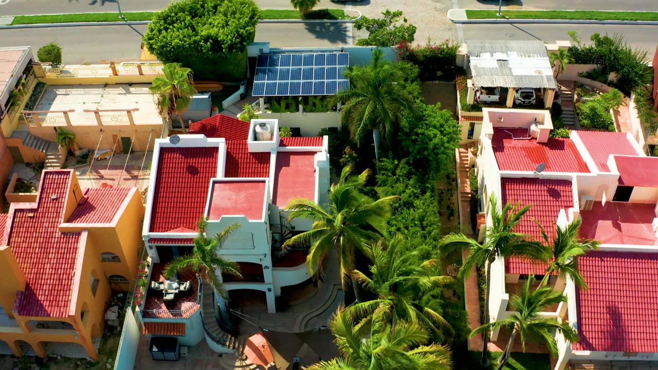 Overhead neighborhood view with red roofs, palm trees, and street traffic.