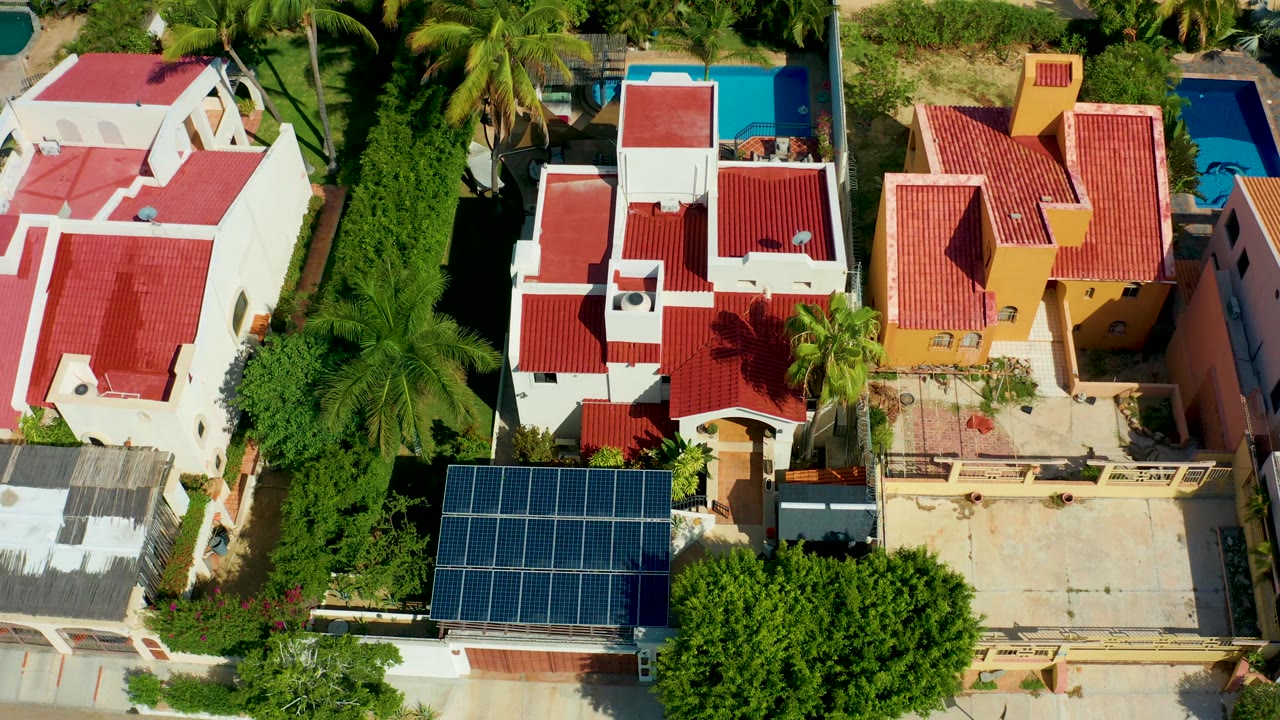 Overhead neighborhood frame with red roofs, palms, blue pool, and solar panels.