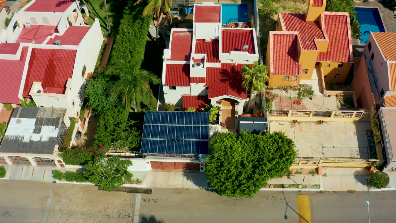 One second into the clip, the San Jose Del Cabo rooftops remain centered while the palm fronds shift slightly over the white homes and no visible people appear.