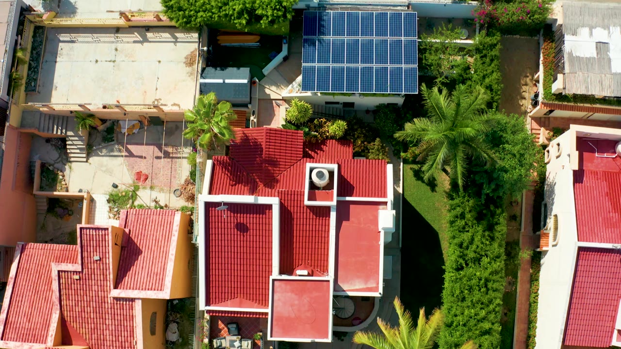 Drone view of red roofs, courtyards, palm trees, and solar panels