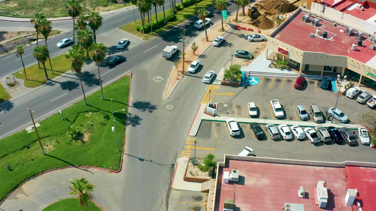 The third frame shows the same San Jose Del Cabo intersection from above, with parked cars in rows, vehicles on the road, palm shadows, red roofs, and no visible people.