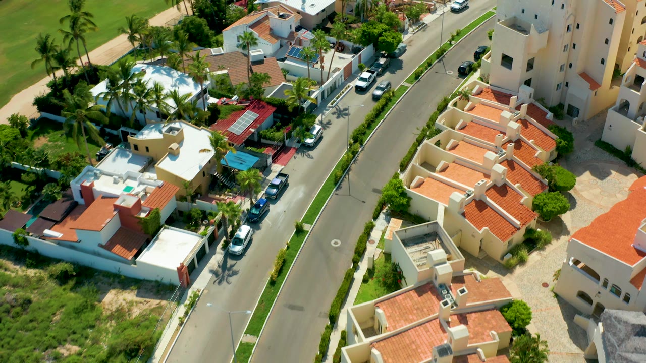 Drone view of neighborhood road with vehicles and palms