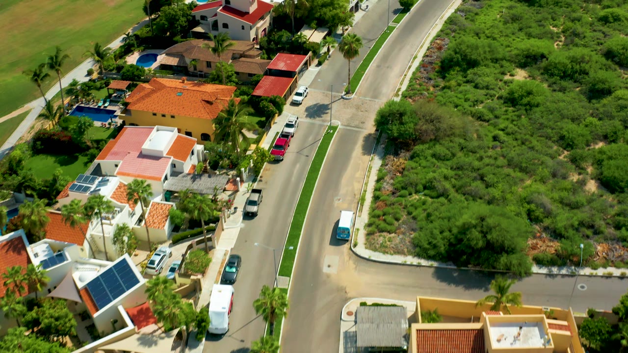 Overhead residential street with houses, palms, and a vehicle on the road.