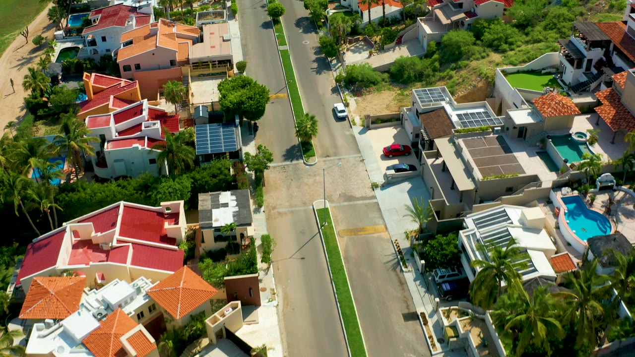 Aerial view of a residential street bordered by homes with tile roofs and palms.