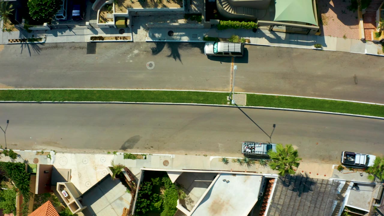 White van drives along the upper road in a top-down residential street view.