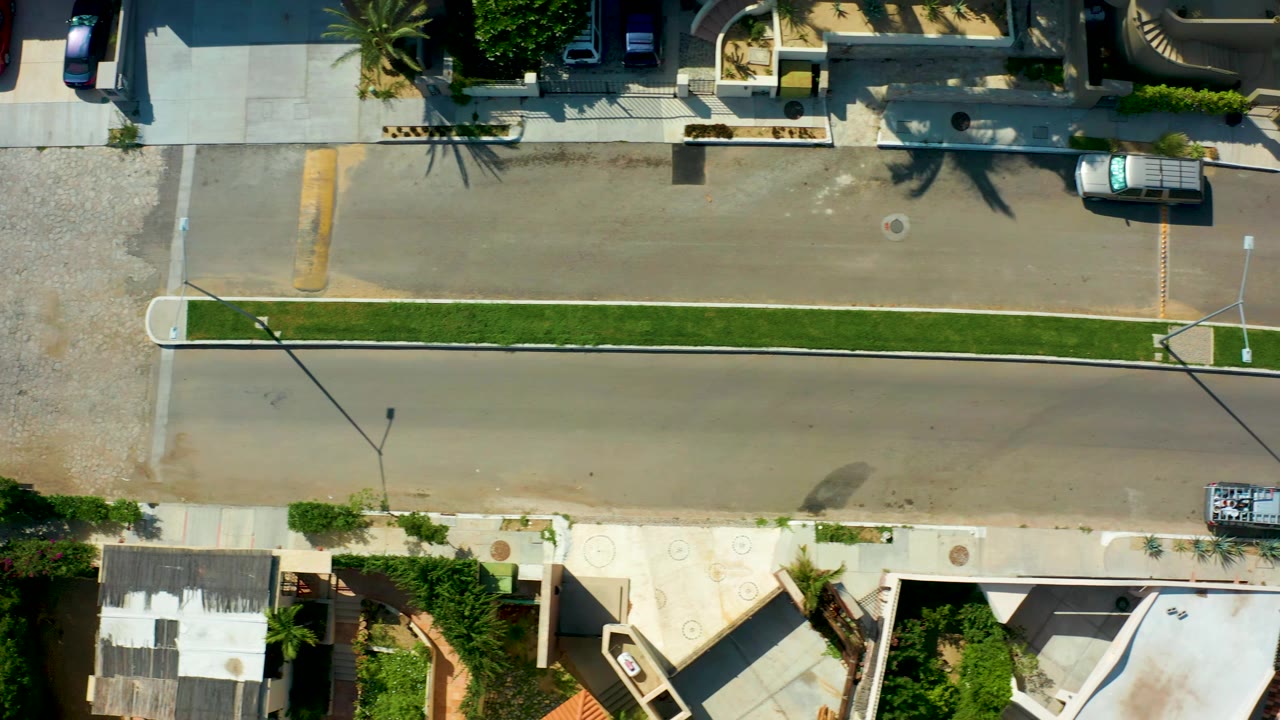 Aerial road view with median, sidewalks, and a vehicle near the curb