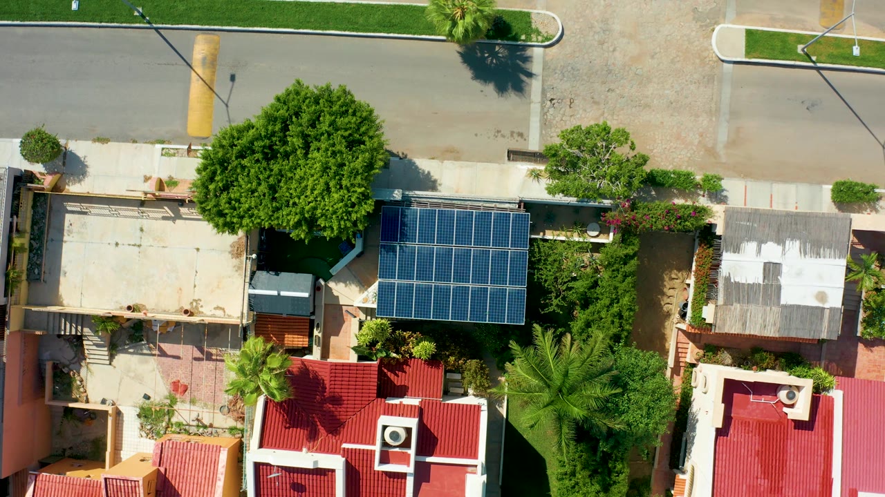 The San Jose Del Cabo overhead view continues with the solar panel array near center, red-roofed houses at the bottom, trees filling the right side, and no visible people.