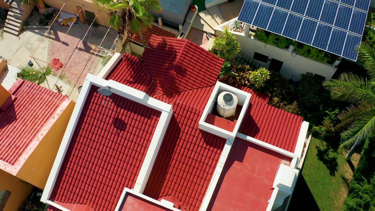 Overhead red tiled roof with solar panels and palm shadows nearby.