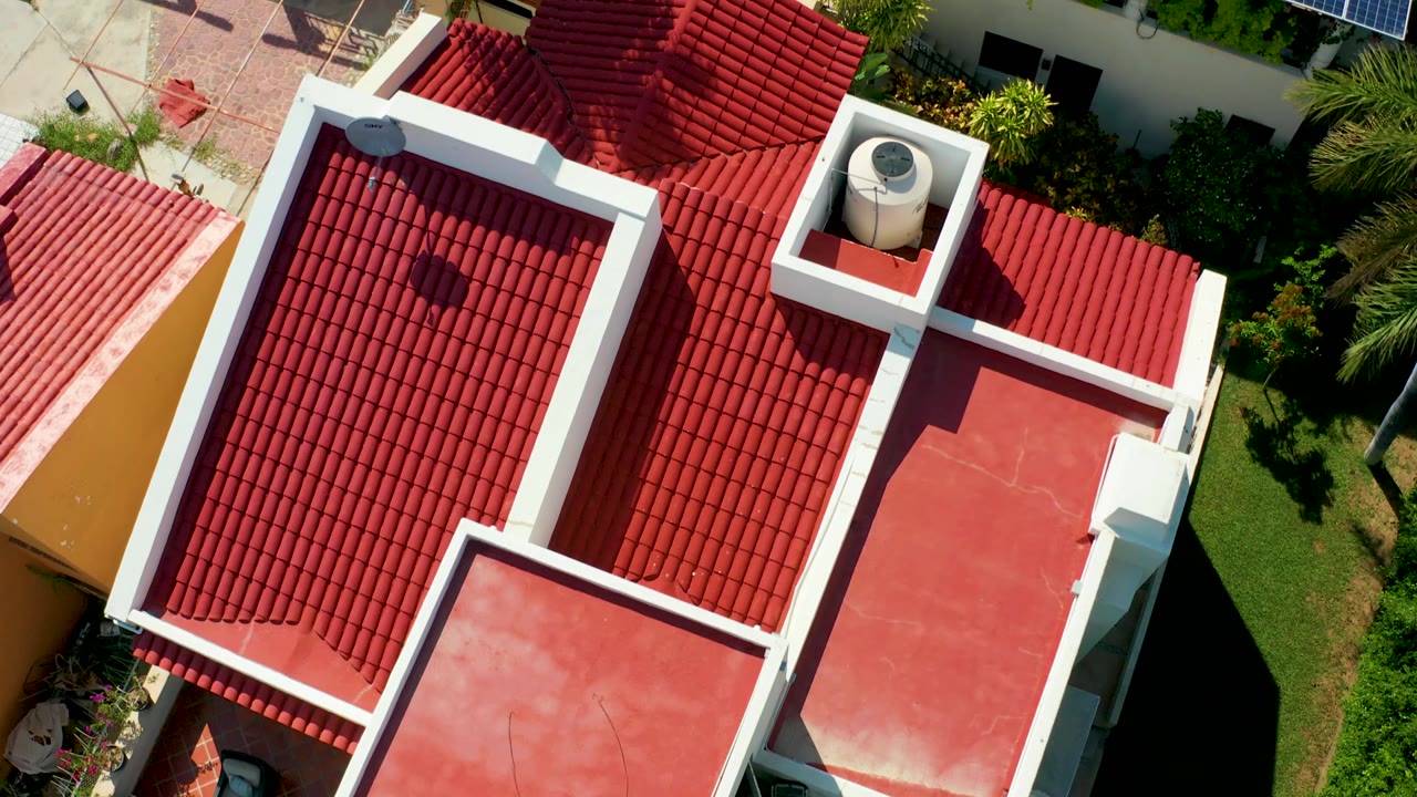Top-down rooftops with red tiles, white trim, and garden areas.