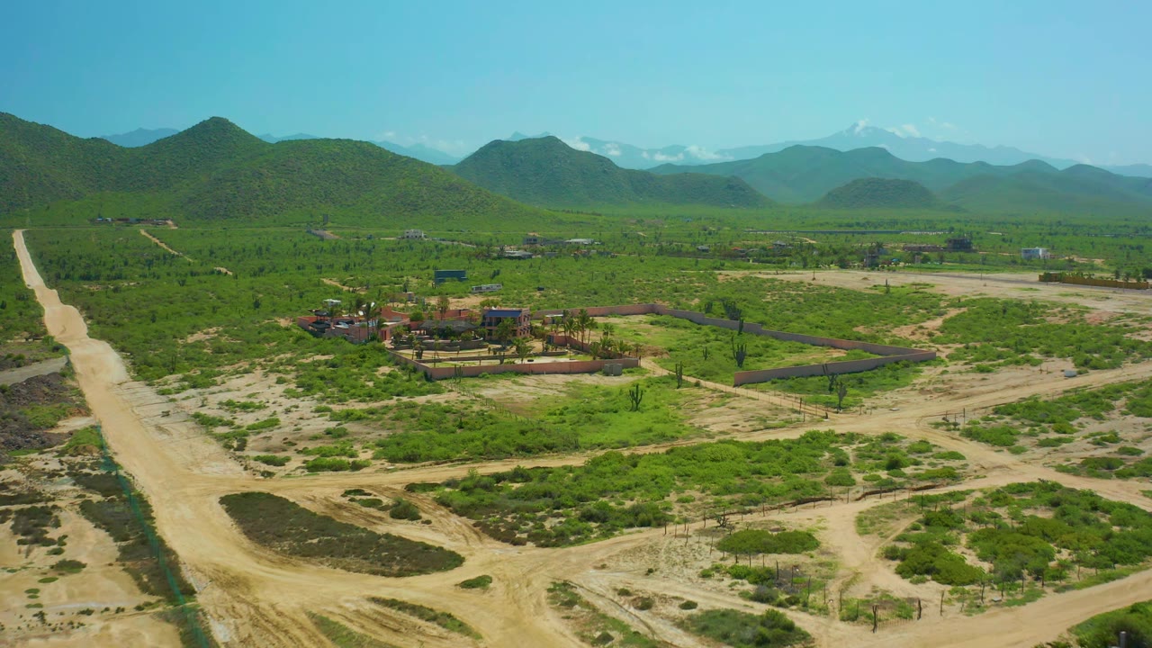 Drone view of rural roads crossing green vegetation toward mountains