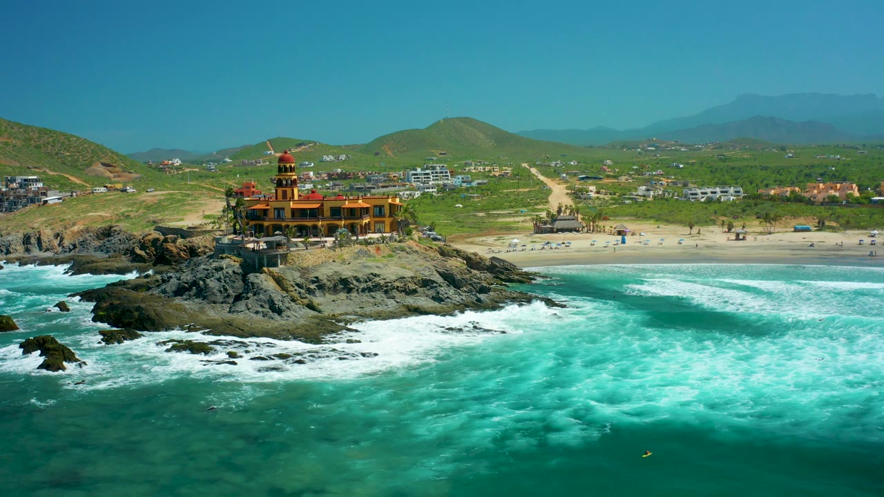 Aerial coastline with lighthouse, rocks, beach, and breaking surf