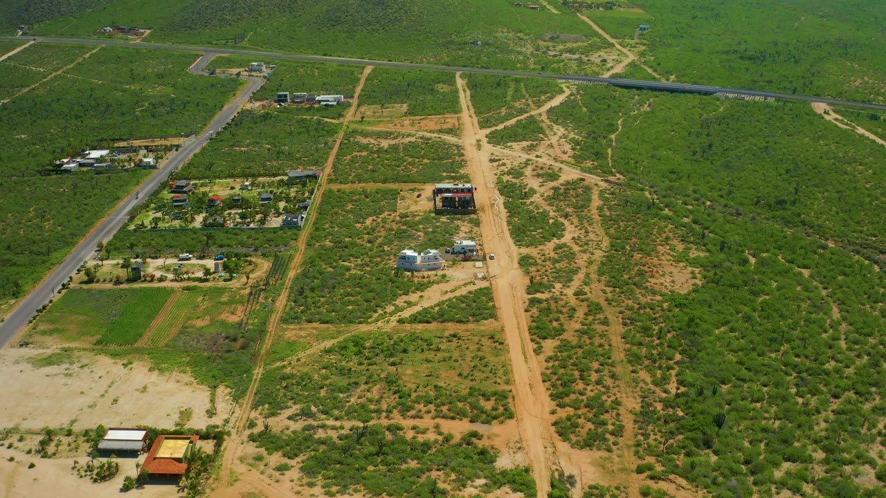 Aerial farmland crossed by paved road and sandy dirt paths
