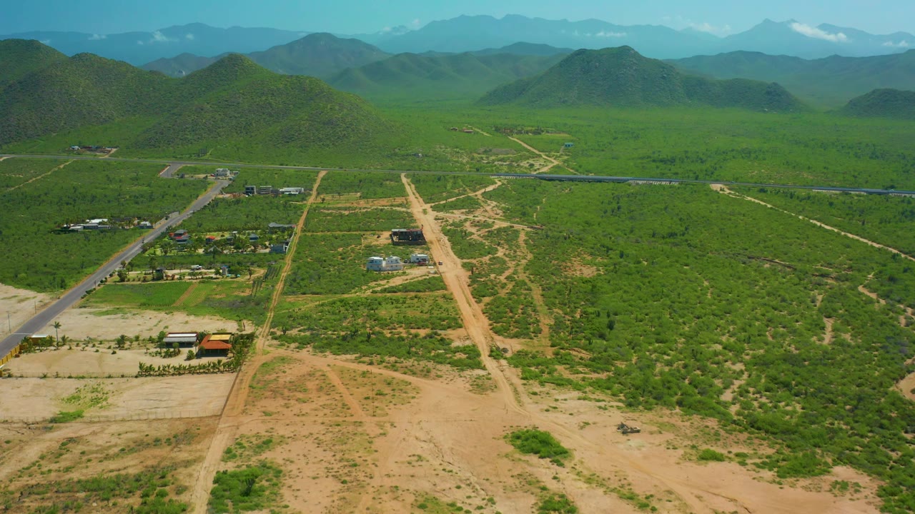 Third frame shows Cerritos Beach inland terrain from above, with pale dirt roads running toward small structures, green scrub covering the valley, layered hills on the horizon, and no visible people.