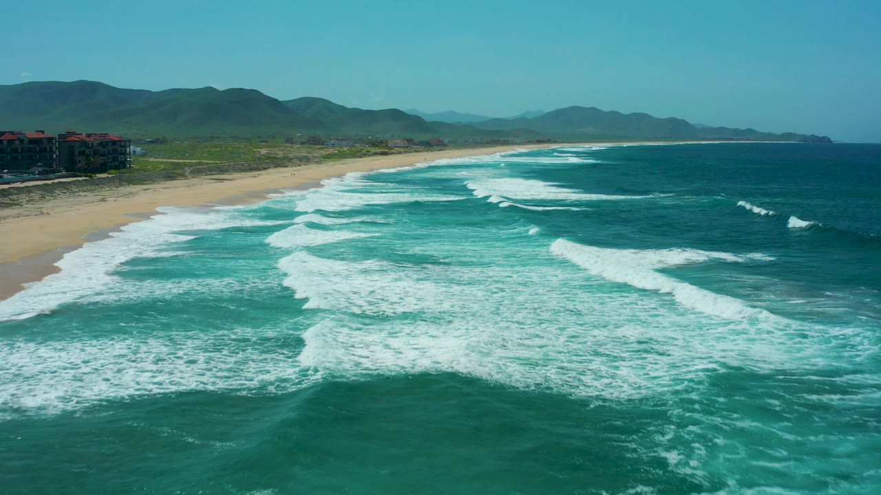Aerial beach view with surf foam spreading across turquoise water