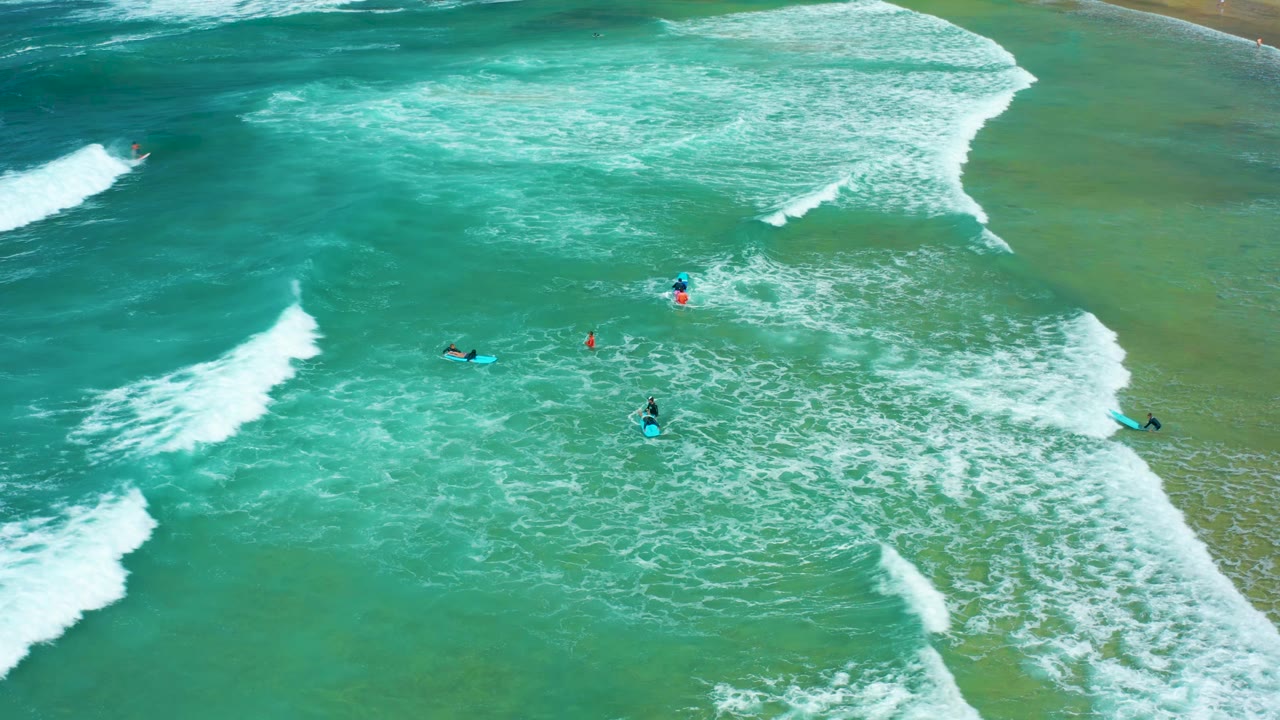 Surfers on boards in foamy turquoise surf