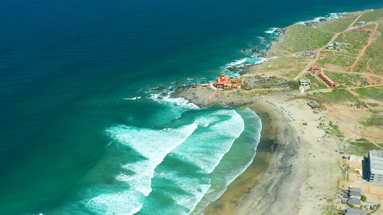 Aerial coastline with broad foam lines and sparse beach development.