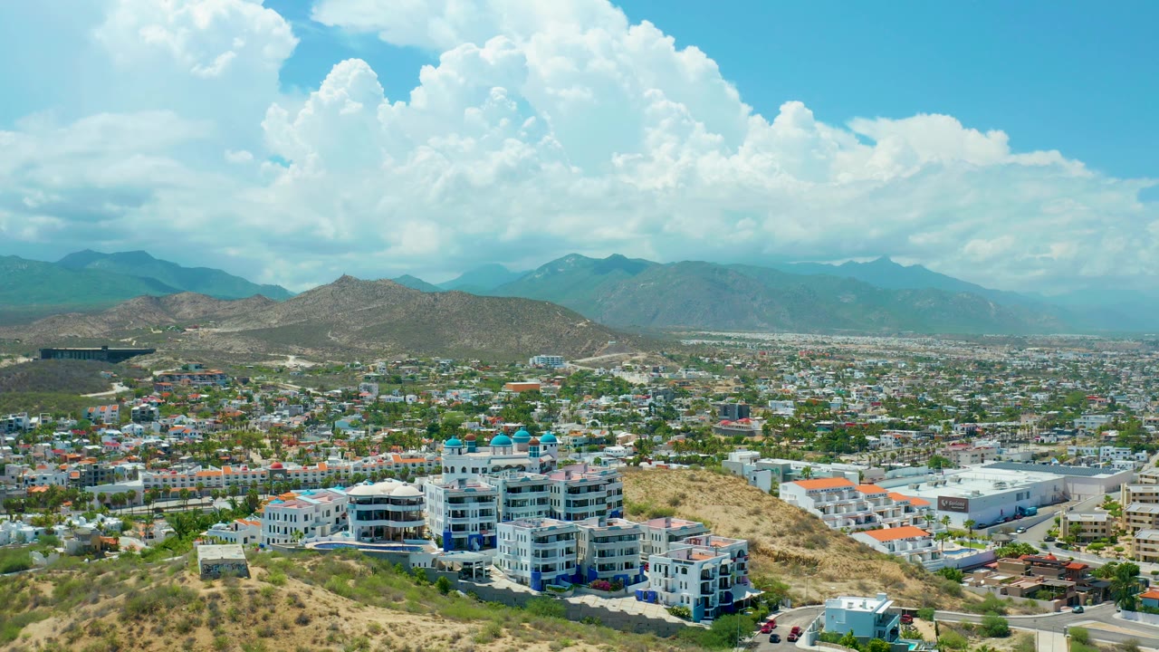 Static aerial over hillside city with cloud-filled sky
