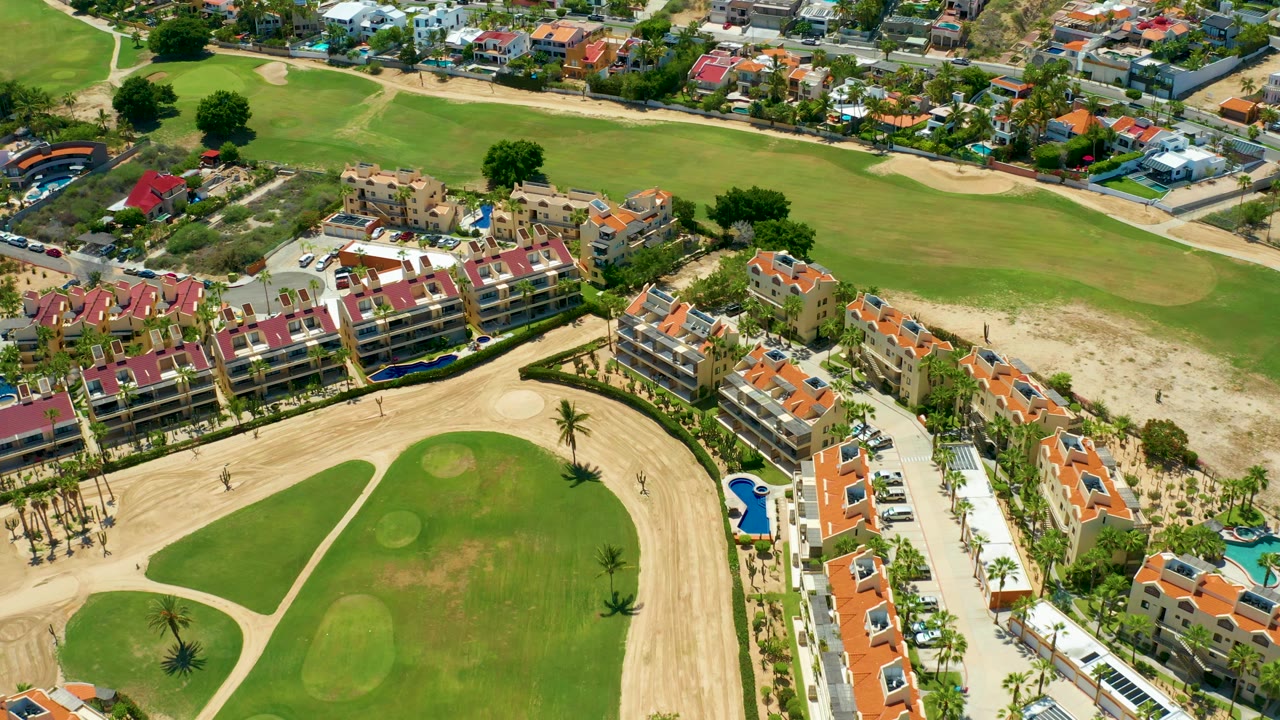Overhead golf course with apartment buildings and orange roof houses.